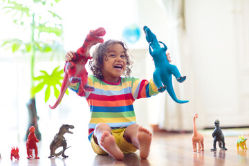 Child playing with toy dinosaurs. Kids toys.