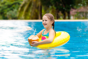 Child with coconut drink. Kids in swimming pool.