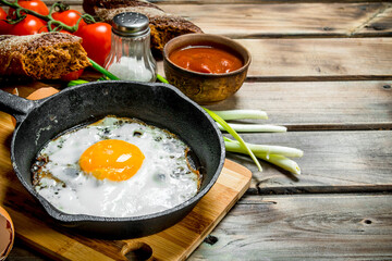 Fried egg in a pan with bread, tomatoes and green onions.
