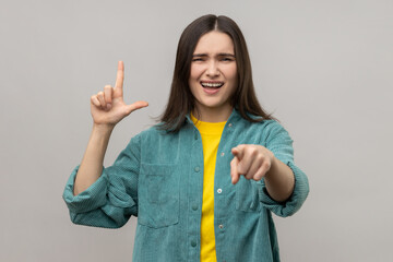 Disrespectful rude young woman showing loser gesture and pointing on you, abuser, mocking your...