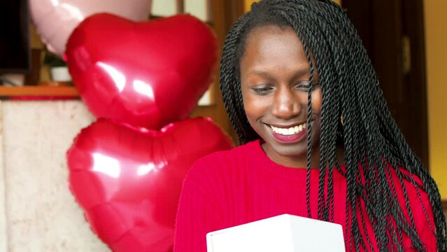 Young woman holding a present  during valentine's day big heart balloons background
