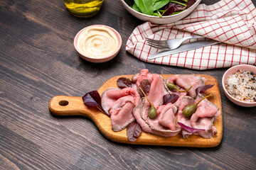 Meat dish Roast beef sliced with capers and spinach leaves. keto diet food