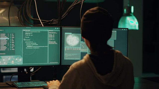Skilled male hacker exploiting system vulnerability and breaking into firewall encryption, using hacktivism concept to steal information. Young man planting pc malware on computer server.