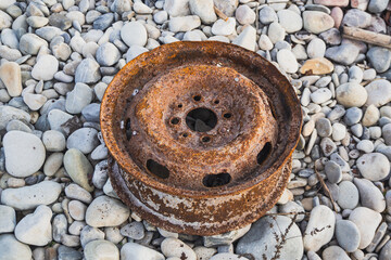 Old car wheel, rusty car alloy rim on stones by the river