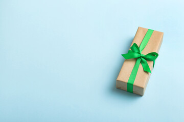 Wrapped christmas or other holiday handmade present in craft paper with colored ribbon. Present box, decoration of gift on table, top view with copy space