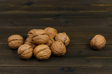 A bunch of walnuts on a dark brown wooden table. Close up.