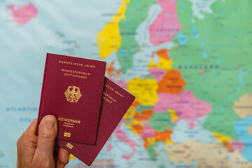 Male hand with two german passports over map of europe. Close up.