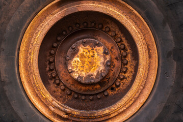 Fototapeta na wymiar Full frame circular background texture of the rusted rim and giant rubber tire of an old mining truck