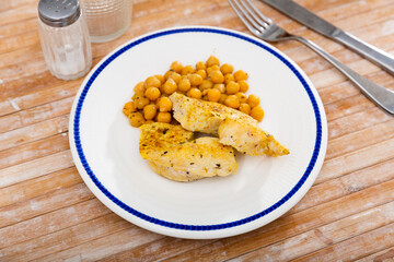 Naklejka premium Homemade roasted meat of chicken with chickpea served on a plate in a cafe