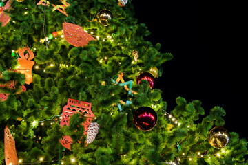 Christmas tree decorated with luminous garlands at night in the park at the Christmas exhibition. Golden and red Christmas toys