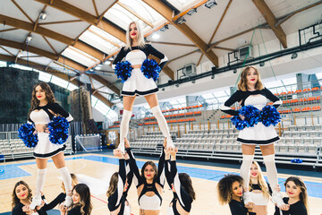 Full shot of three cheerleaders standing on top of their friends' hands. Sport concept. High...