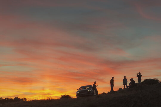 Group of friends near car at sunset