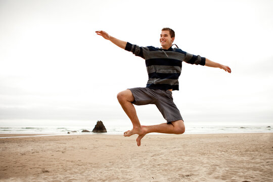 Male doing a heel click on a beach.