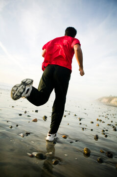 A man runs on the beach in Carlsbad, CA.