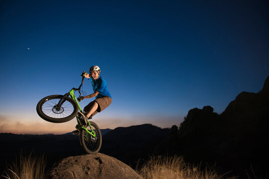 A man performs trial bike standing on a rock at El Diente, Jalisco, Mexico.
