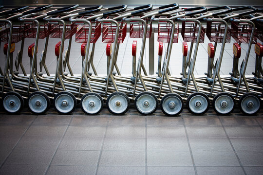 A row of empty luggage carts in airport.