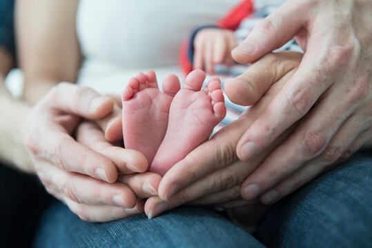 Parents holding the feet of their newborn baby boy
