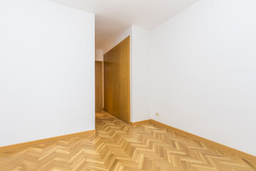 Empty room with oak flooring and dressing room with cabinets of the same material