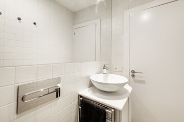 Bathroom with white wood cabinets, white porcelain hemispherical sink, large built-in mirror, tile work, and white wood door