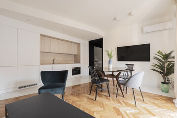 Studio apartment with open-plan kitchen, round glass dining table and varnished oak parquet flooring