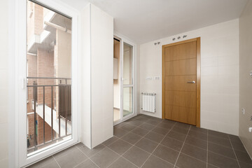 Empty room to install the kitchen with clothesline with white aluminum and glass sliding doors and oak wood access door