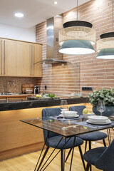 Studio apartment with open plan kitchen with glass dining table and blue fabric chairs