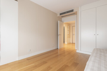 Bedroom with a single bed with a light bedspread and a built-in wardrobe with white doors and air conditioning through ducts in the false ceiling