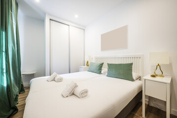 Bedroom with a white wooden double bed with a barred headboard, a built-in wardrobe with sliding doors and white bedside tables
