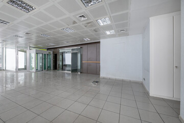 An empty place with technical ceilings, stoneware floors and an entrance with a metal detector