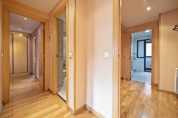 Distributor corridors with fuchsia painted walls of a house with access to several rooms with access doors and beech wood cabinets and oak parquet floors