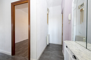 Hall of a house with a wooden sideboard and white marble with mirrors