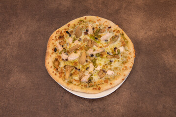 An individual chicken pizza with pesto sauce