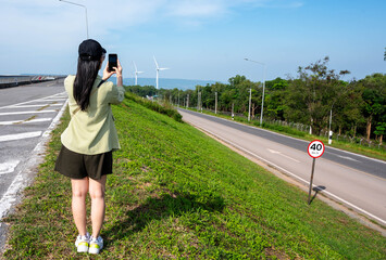Asian woman use smartphones to take photo with the natural view at the  windmill Lam Takhong, Nakhon Ratchasima, Thailand Khao Yai Thiang,