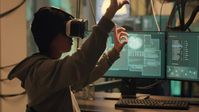 Male spy planting virus with vr headtset at night, using virtual reality to hack government database. Dangerous hacker doing cyber espionage on dark web, illegal harassment. Handheld shot.