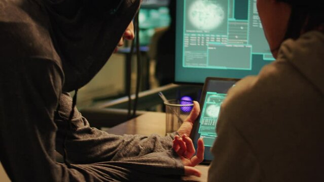 Cyber criminals using knowledge of computer systems to access sensitive information illegally, making online threats and asking ransom. Male thief hacking security network at night. Handheld shot.