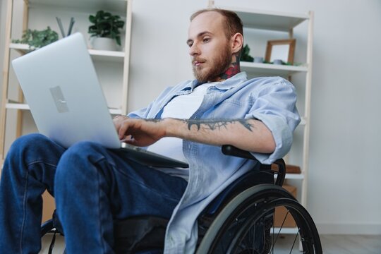 A man in a wheelchair freelancer works at a laptop at home, work online, social networks and startup, copy space, integration into society, concept of health disabled person, real person close-up