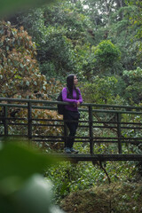 Black-haired woman leaning on a bridge admiring the natural beauty of a forest in Costa Rica