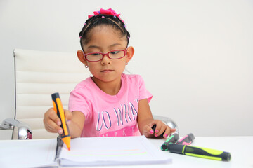 4-year-old brunette Latina girl with autism spectrum disorder ASD like Asperger, Rett and Heller draws at a desk, plays with colors alone antisocial