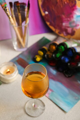 Glass of tasty wine, colorful paints and canvas, above view. Space for text