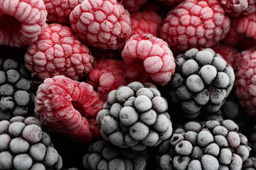 Tasty frozen raspberries and blackberries as background, top view