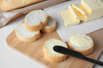 Fototapeta na wymiar Tasty cut baguette with fresh butter on white table, closeup