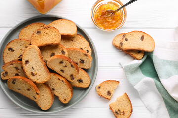 Sweet hard chuck crackers with raisins and jam on white wooden table, flat lay
