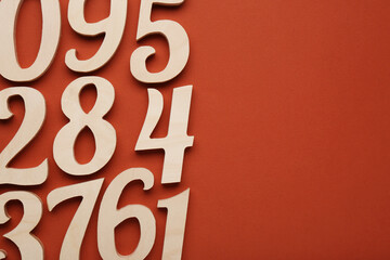 Wooden numbers on brown background, flat lay with space for text