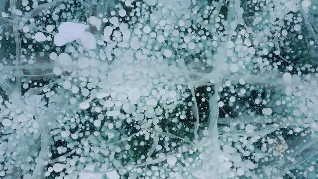 Frozen methane bubbles and cracks in the ice on Lake Baikal Siberia Russia. Natural cold background of ice. Winter abstract background. High quality 4k footage