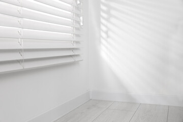 Obraz premium Window with closed horizontal blinds near white wall indoors