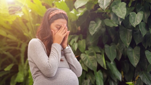 Sad and stressed Asian pregnant woman.
 Pregnant woman hold forehead. healthy and sickness concept.