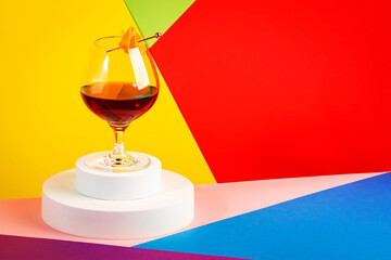 Martinique alcoholic cocktail with golden rum, red vermouth, liqueur, bitter and orange zest. Modern style still life on trendy bright multi-colored background