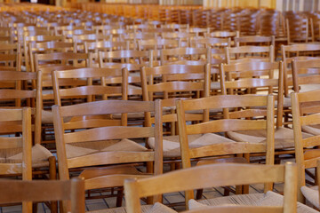 Selective focus view at row of chairs without people for worshipper at nave of Protestant Church. 