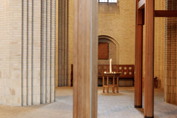  Interior view at the aisle and nave area with single table and candle  and background of arch door...