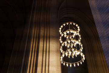 Dark atmosphere and selective detail of lamp chandelier, cream brick vault, arch, rib wall, column...